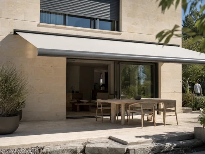 Store banne déployé au-dessus d’une terrasse, volets aluminium sur la façade