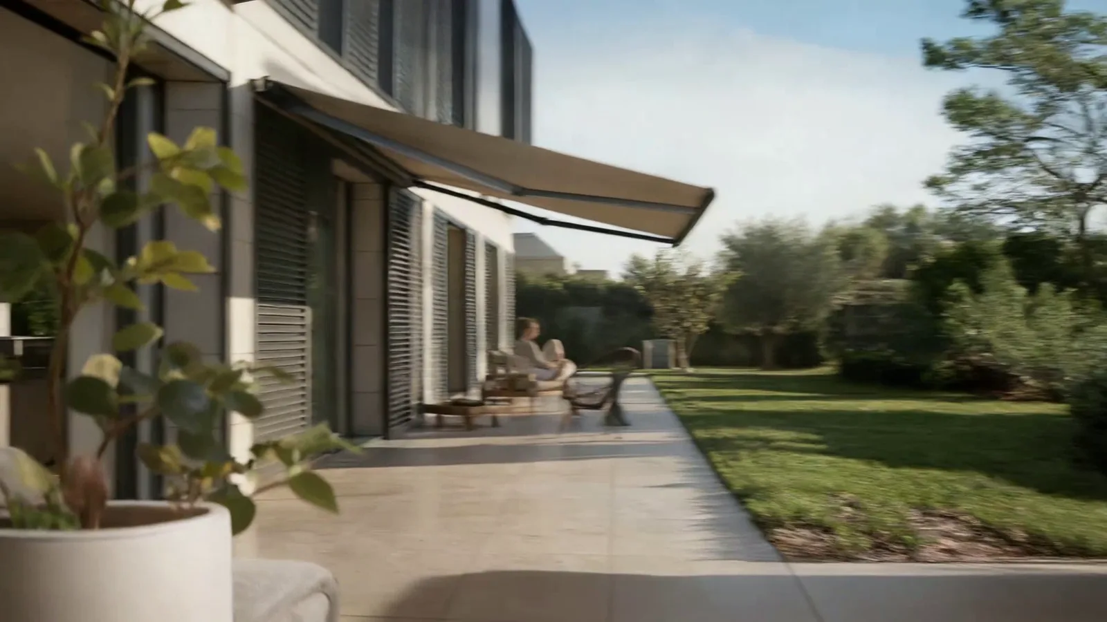 Store banne déployé au-dessus d’une terrasse, volets aluminium sur la façade